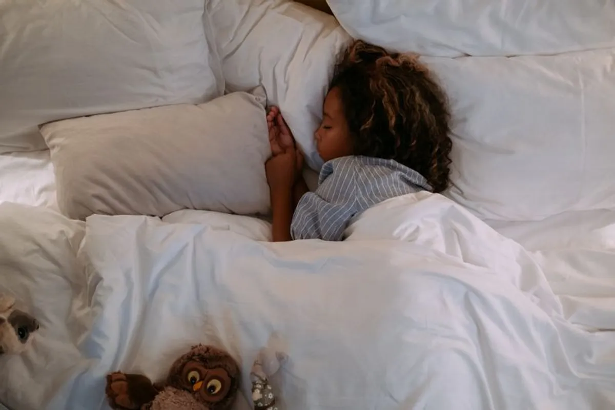 Kind schläft friedlich im Bett mit Plüschtier